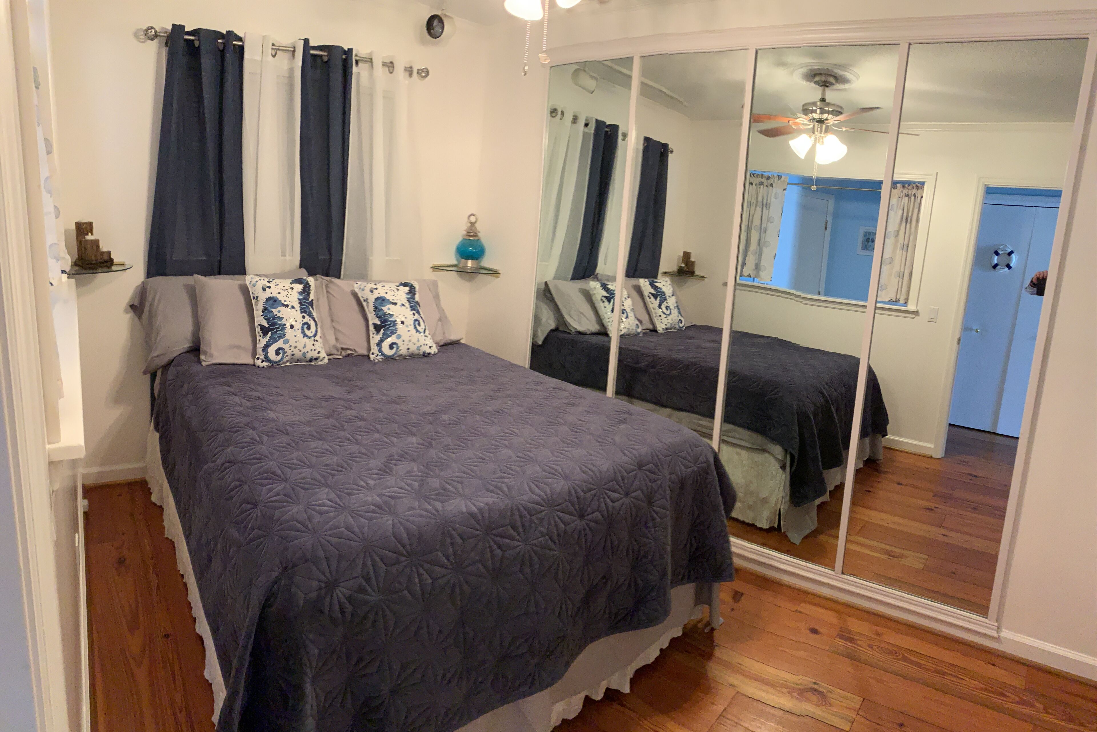 Ein Schlafzimmer mit einem großen Bett, zwei Nachttischen, einem Spiegel und einem Deckenventilator.
