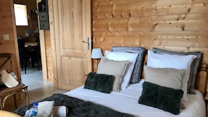 A wooden room with a bed, a chair, and a desk.