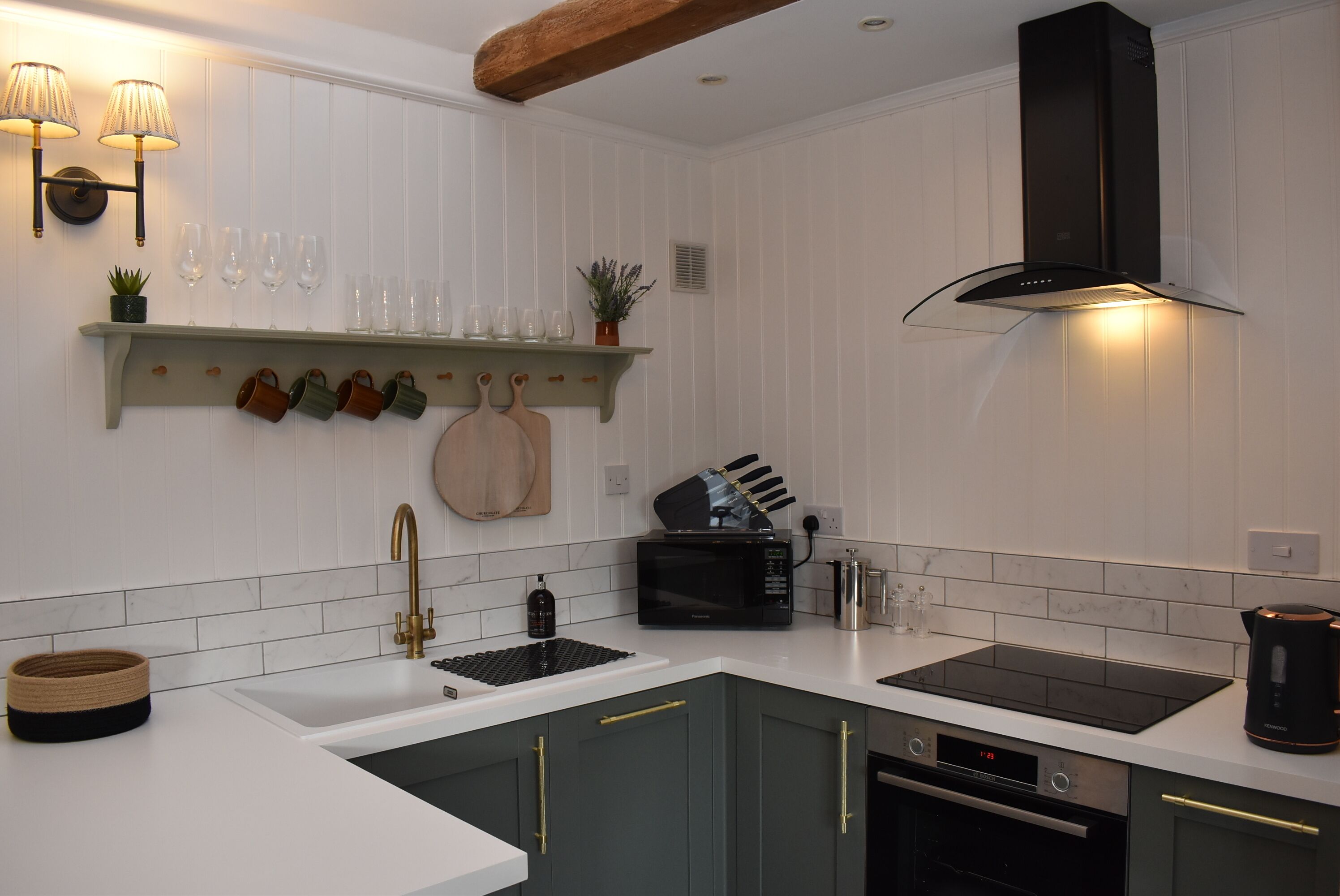 A modern kitchen with white cabinetry, a black microwave, a built-in oven, and a stainless steel sink.