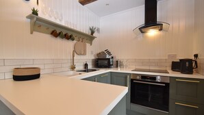 A modern kitchen with a large island, built-in appliances, and a unique wine rack. - Daisy (Rye)