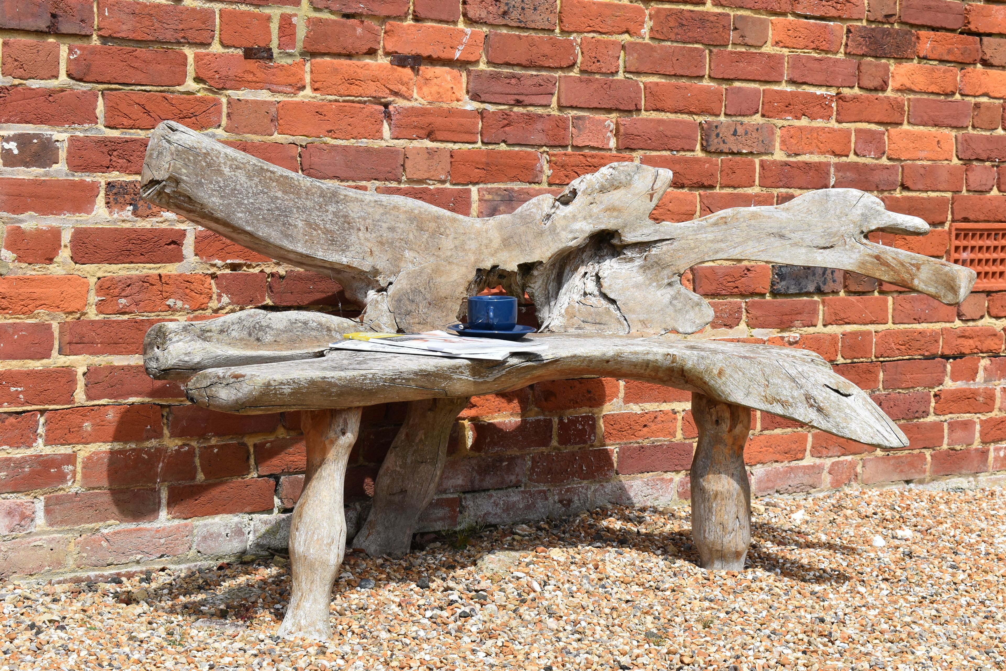 A rustic wooden bench with a blue object on it, set against a brick wall.