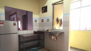 Cozinha compacta com geladeira, pia e piso ladrilhado.