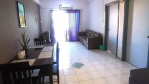 Uma sala de estar espaçosa com área de jantar, um ventilador de teto e uma grande janela com cortinas.