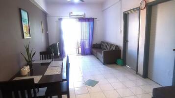 A spacious living room with a dining area, a ceiling fan, and a large window with curtains.