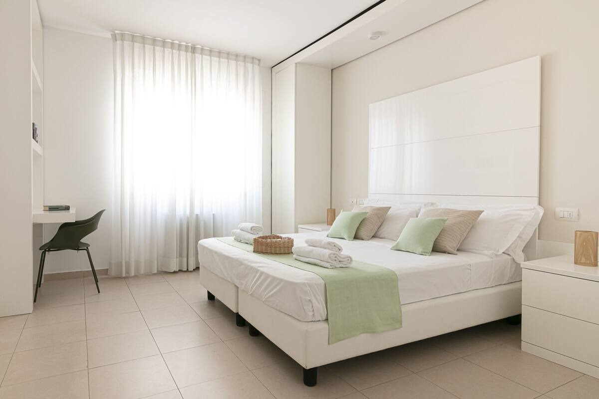 A modern bedroom with a large bed, a desk, and a chair.