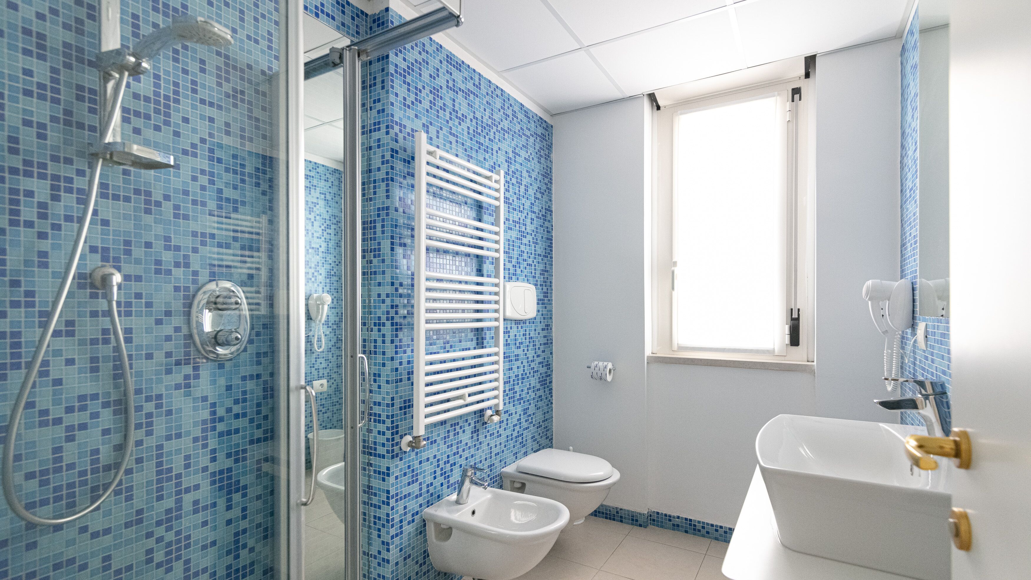 A bathroom with a shower, toilet, bidet, and sink.
