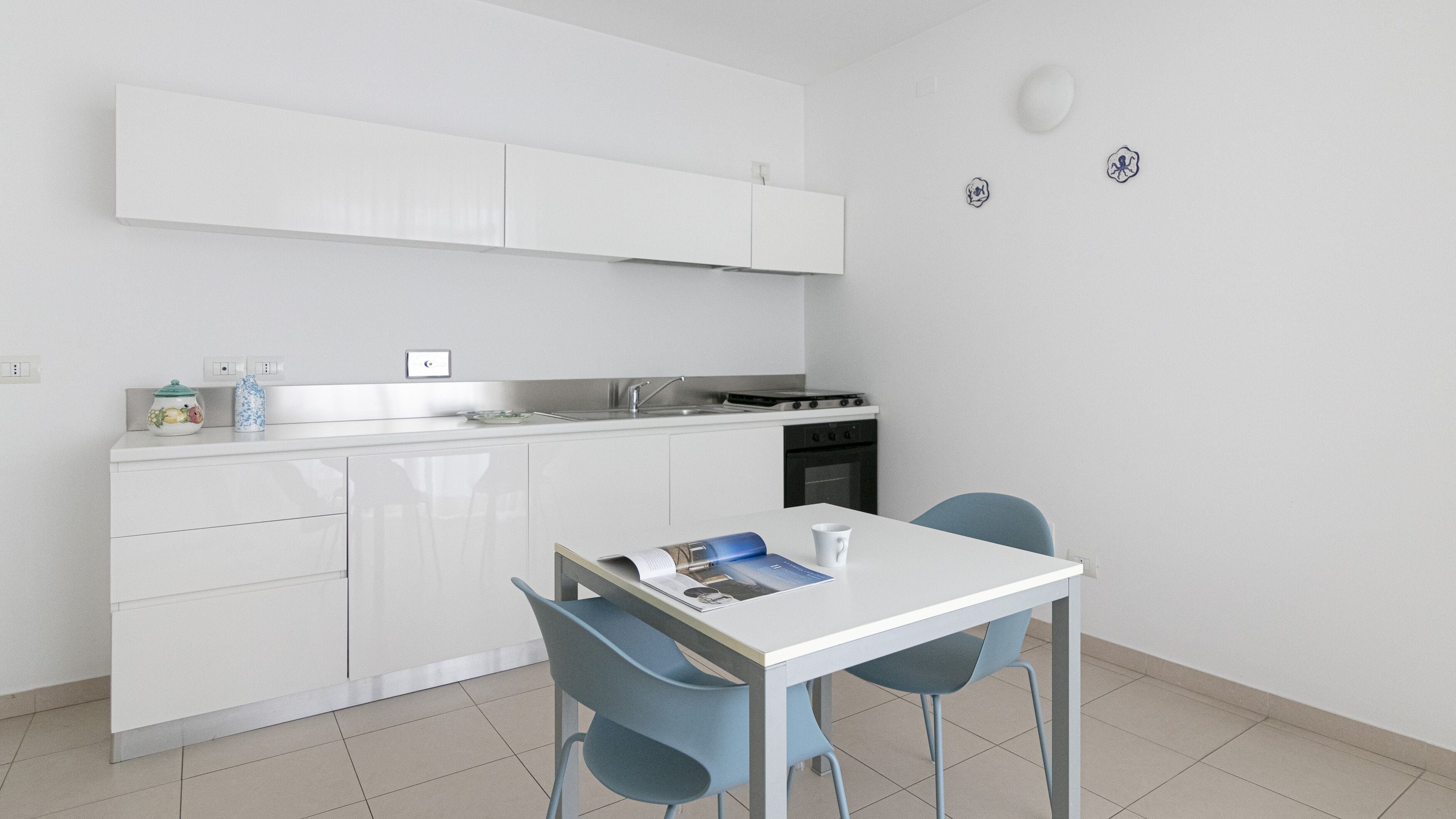 A modern kitchen with white cabinets, a stove, and a dining area with a table and chairs.