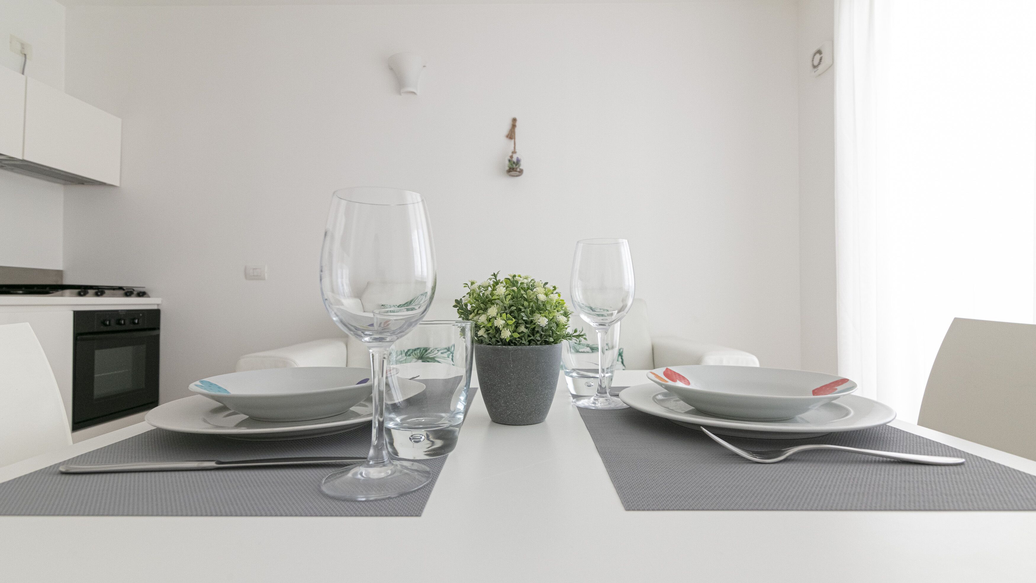 A dining table set with plates, glasses, and a small potted plant.