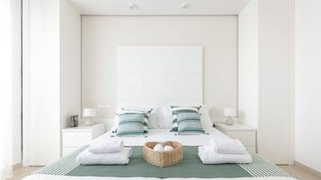 Ein schlicht eingerichtetes Hotelzimmer mit einem großen Bett, zwei Nachttischen und einem grün gestreiften Teppich.