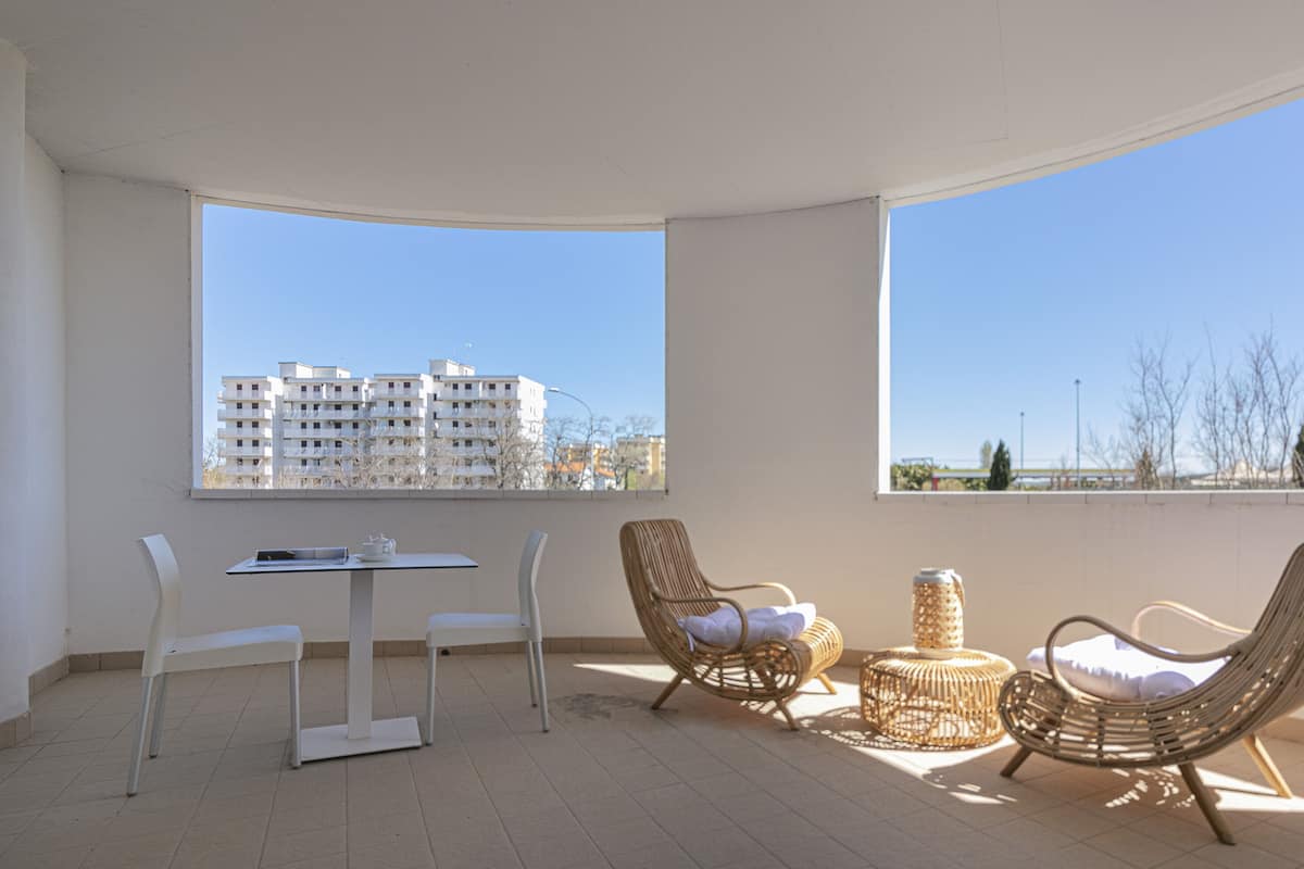 A balcony with wicker chairs, a small table, and a basket.