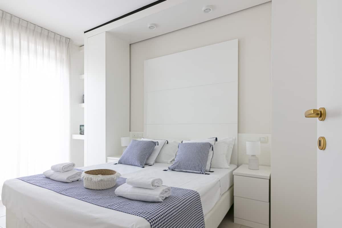 A modern hotel room with a large bed, white walls, and a simple, clean design.