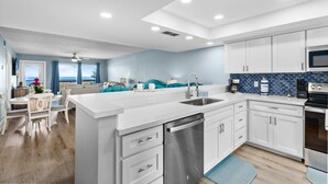 A modern kitchen with white cabinetry, a stainless steel dishwasher, and a blue backsplash. - Stunning Remodeled Condo on the Beach! Resort Pools, Hot Tubs, Tennis Courts & More! Dog-Friendly! (South Padre Island)