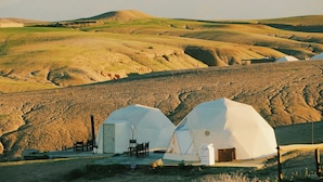 Two dome-shaped yurts with attached structures, set in a hilly landscape with distant mountains. - Emeraude Camp Agafy (Agafay)