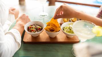 Uma mesa com três tigelas de comida, um copo de bebida e uma tortilla chip.