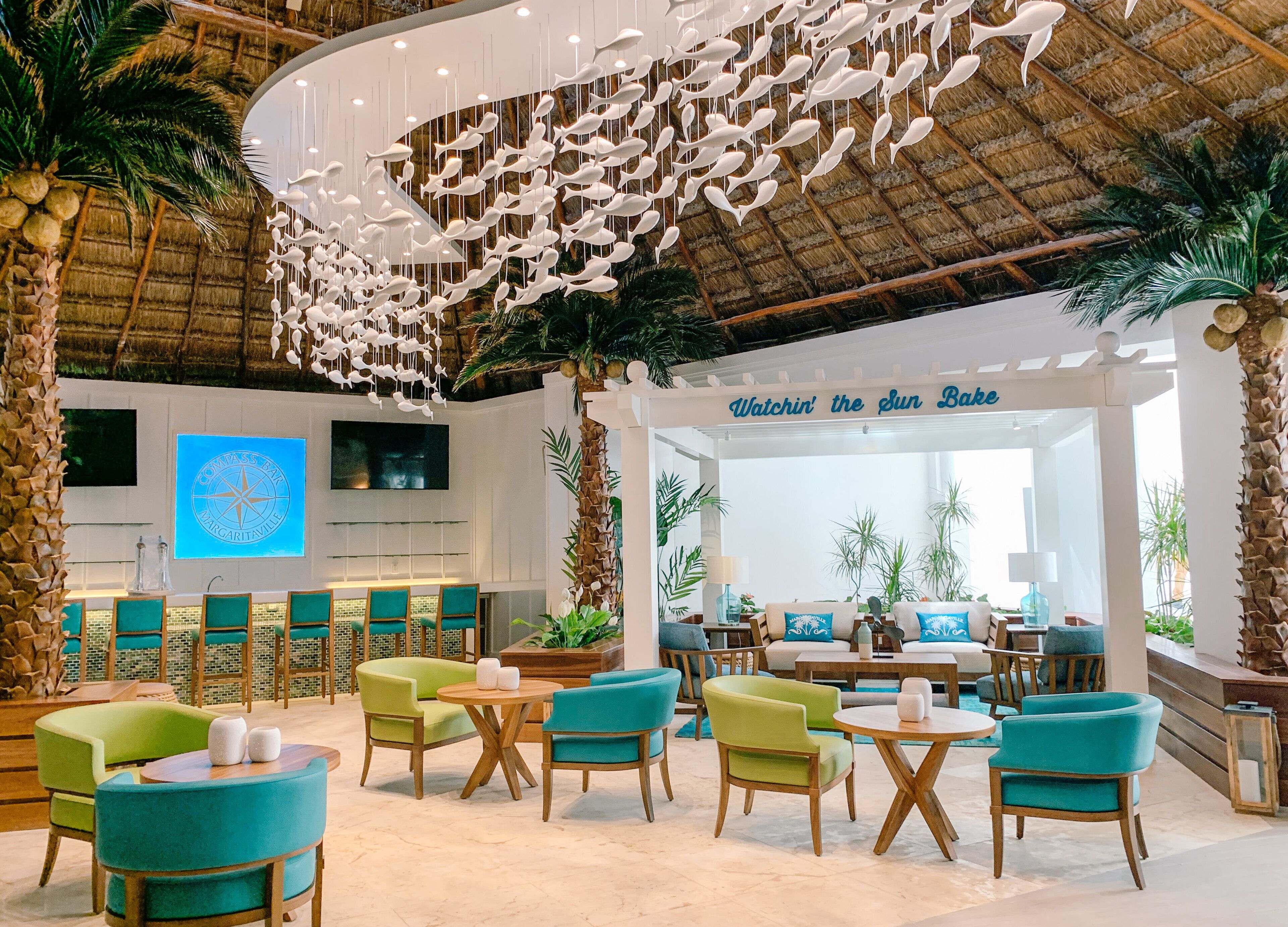 Un amplio vestíbulo con temática tropical, que presenta una gran escultura de peces, una zona de bar y asientos cómodos.