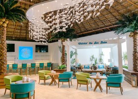 Un amplio vestíbulo con temática tropical, que presenta una gran escultura de peces, una zona de bar y asientos cómodos.