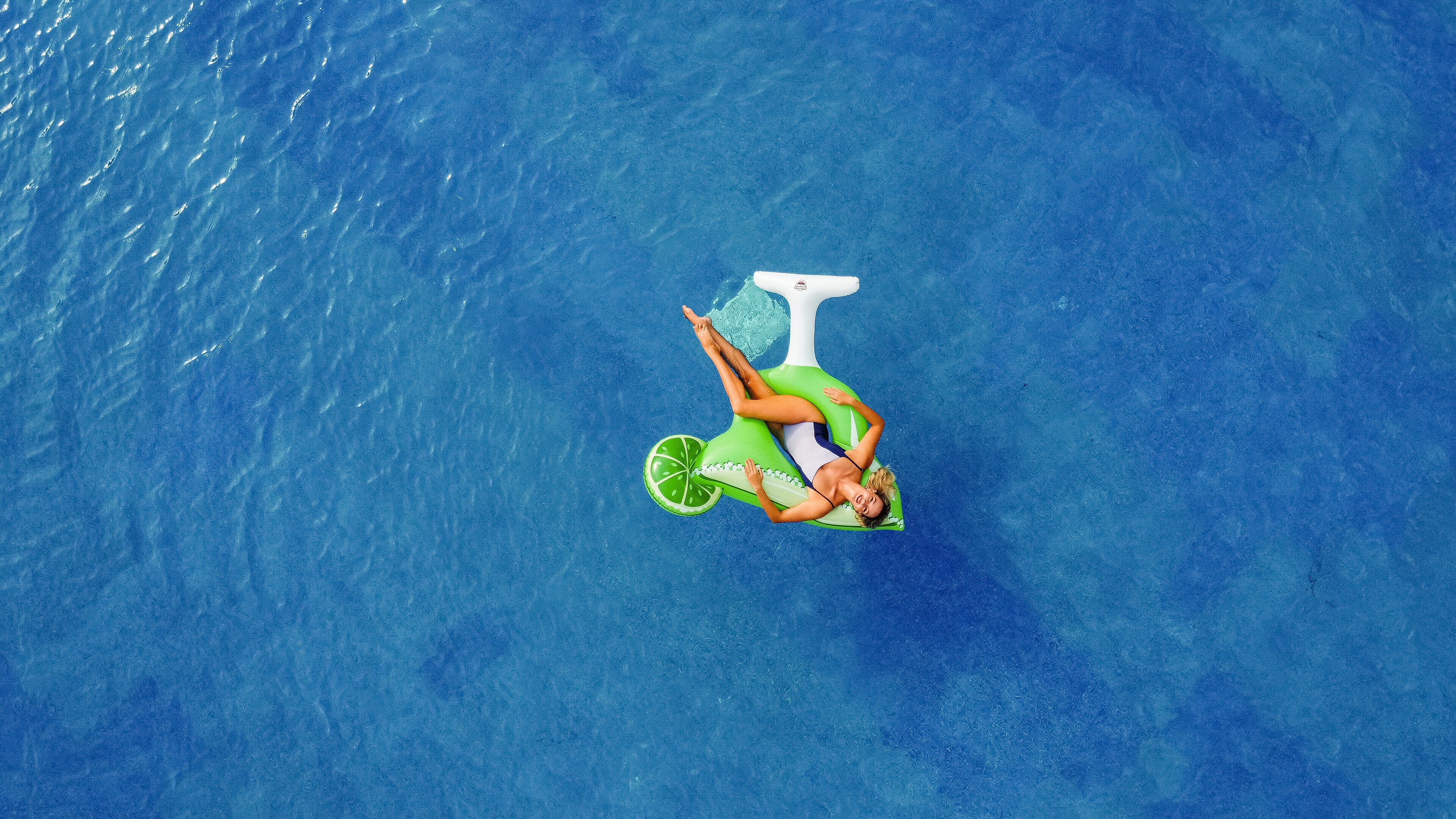 Eine Person liegt auf einer schwimmenden Plattform in einem großen Gewässer.