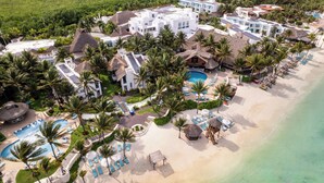 An aerial view of a resort with multiple buildings, a beach, and a swimming pool area.