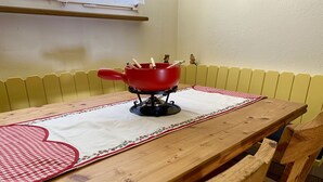 Taula de dinar de fusta amb un mantell daurat i blanc a escacs, un búllet elèctric vermell i cadires de fusta.