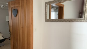 Una porta de fusta amb una decoració de cor, un mirall amb un marc ornamentat i un petit tamboret de fusta.