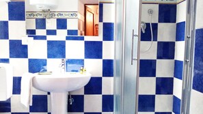 A bathroom with a checkered tile pattern, a white sink, and a glass-enclosed shower. - Carducci bright flat in historic centre (Pistoia)