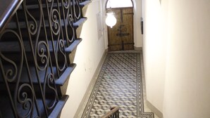 A staircase with ornate metal railings leading to a door with a geometric patterned floor. - Carducci bright flat in historic centre (Pistoia)