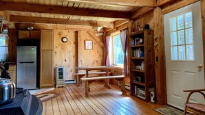 A wooden cabin interior with a kitchen, a dining area, and a bookshelf. - Hiker Heaven!!  Come and enjoy. (Randolph)