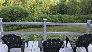 A deck with four Adirondack chairs and a white railing overlooking a lush garden and distant mountains. - Hiker Heaven!!  Come and enjoy. (Randolph)