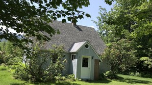 A small, single-story house with a gabled roof, surrounded by lush greenery and trees. - Hiker Heaven!!  Come and enjoy. (Randolph)