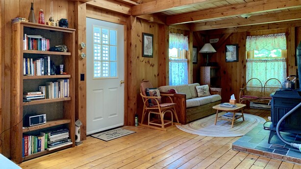 A cozy cabin interior with a wooden bookshelf, a sofa, a fireplace, and a dining area. - Hiker Heaven!!  Come and enjoy. (Randolph)