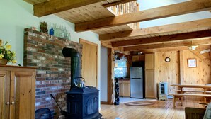 A rustic wooden interior with a brick fireplace, a wooden ceiling, and a kitchen area. - Hiker Heaven!!  Come and enjoy. (Randolph)