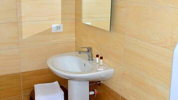 A bathroom with a sink, bidet, and toilet. There is a small stool with a towel.