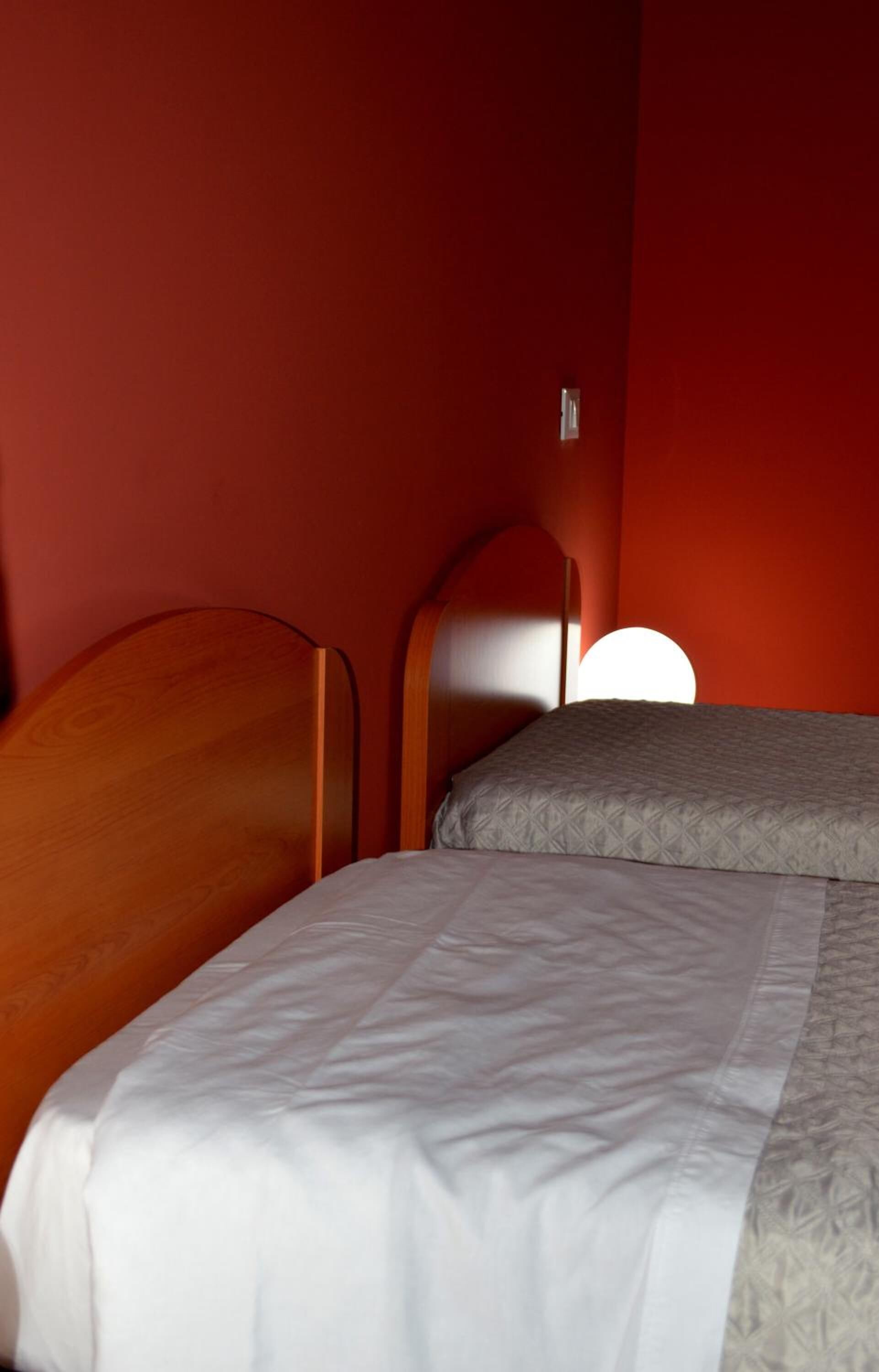 A room with two beds, one with a wooden headboard and the other with a curved headboard.