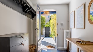 Eine moderne Küche mit einem dunklen Holzschrank, einem Holztisch und Blick auf einen Garten durch eine offene Tür.