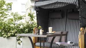 Un espacio exterior acogedor con un banco acolchado, una mesa y una pérgola.