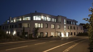 Un edificio moderno de varios pisos con techo plano, ventanas grandes y una entrada bien iluminada.