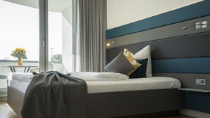 Un dormitorio moderno con cama, mesita de noche y vistas al exterior.