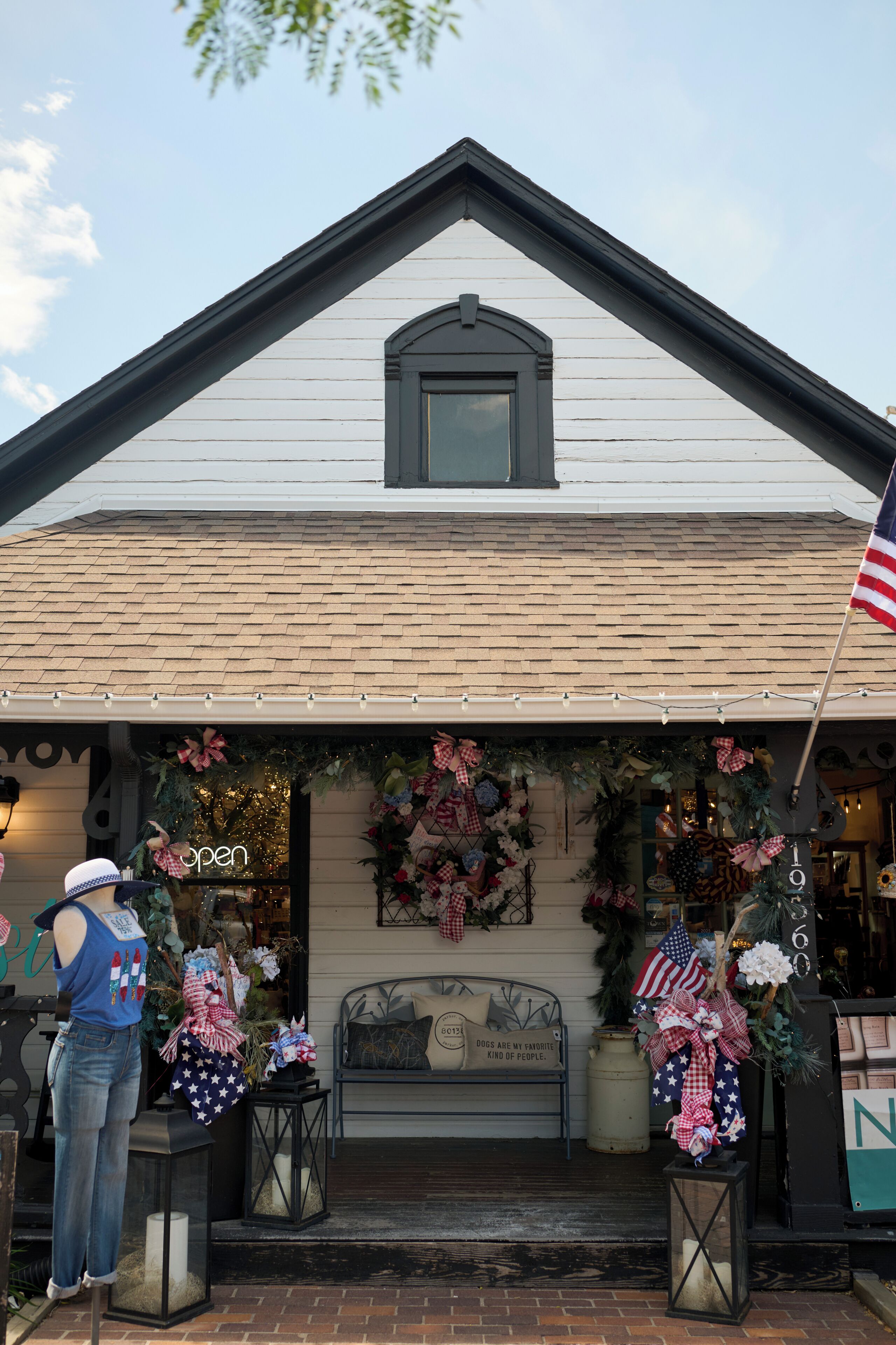 A building with a gabled roof, a front porch with a bench, and a Christmas wreath.