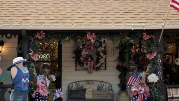 A building with a gabled roof, a front porch with a bench, and a Christmas wreath.