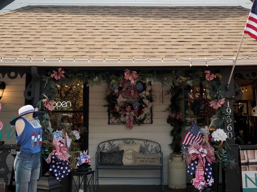 A building with a gabled roof, a front porch with a bench, and a Christmas wreath.