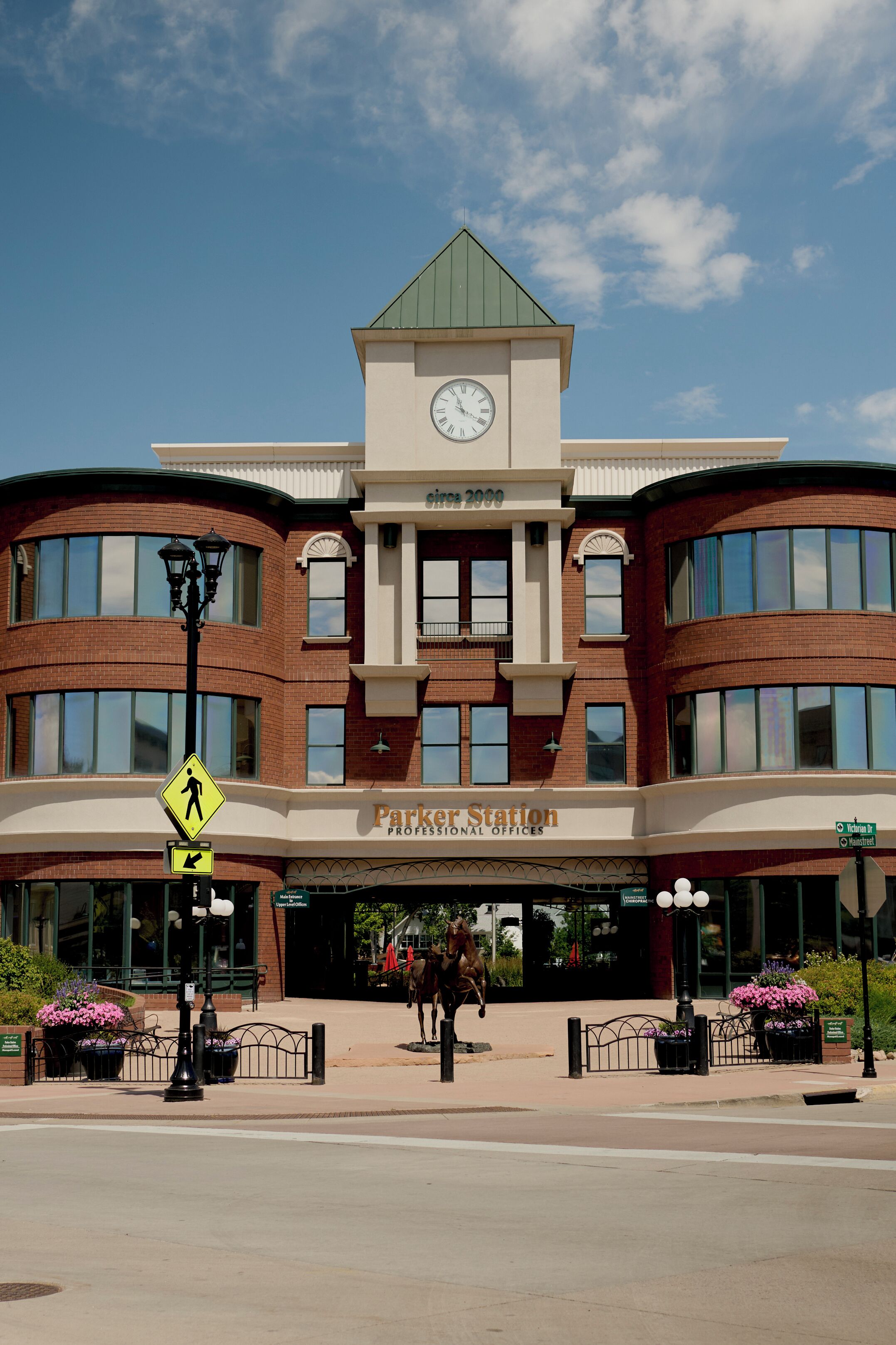 A building with a clock tower, professional offices, and a pedestrian crossing sign.
