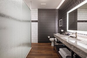 A modern bathroom with a wooden floor, a marble sink, and a black and white patterned wall. - The Parker Hotel (Parker)