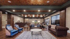 A spacious living room with a high ceiling, wooden flooring, and a patterned rug. There are multiple seating areas including sofas and armchairs. - The Parker Hotel (Parker)
