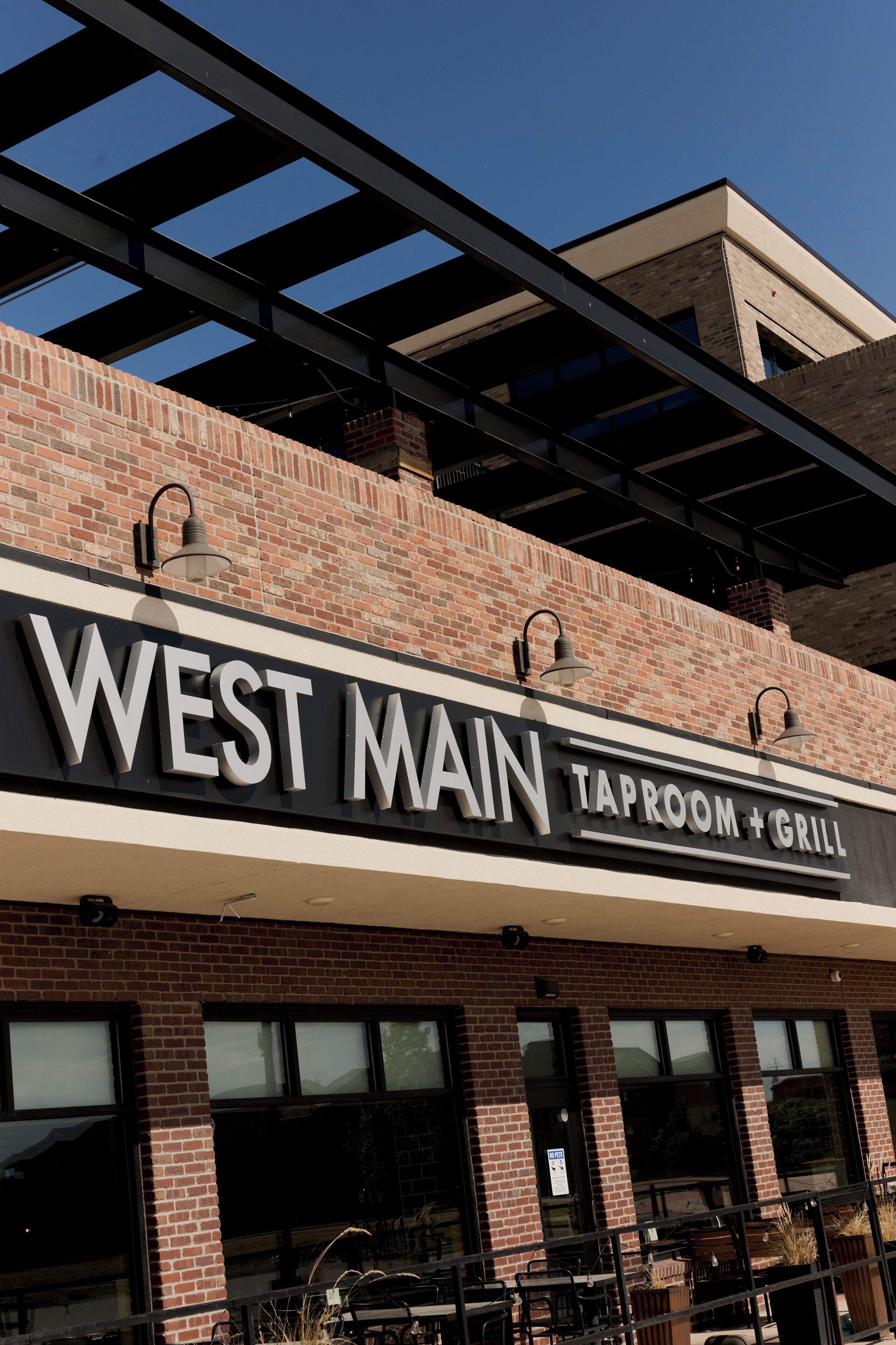 A brick building with a sign that reads 'WEST MAIN TAPROOM + GRILL'.