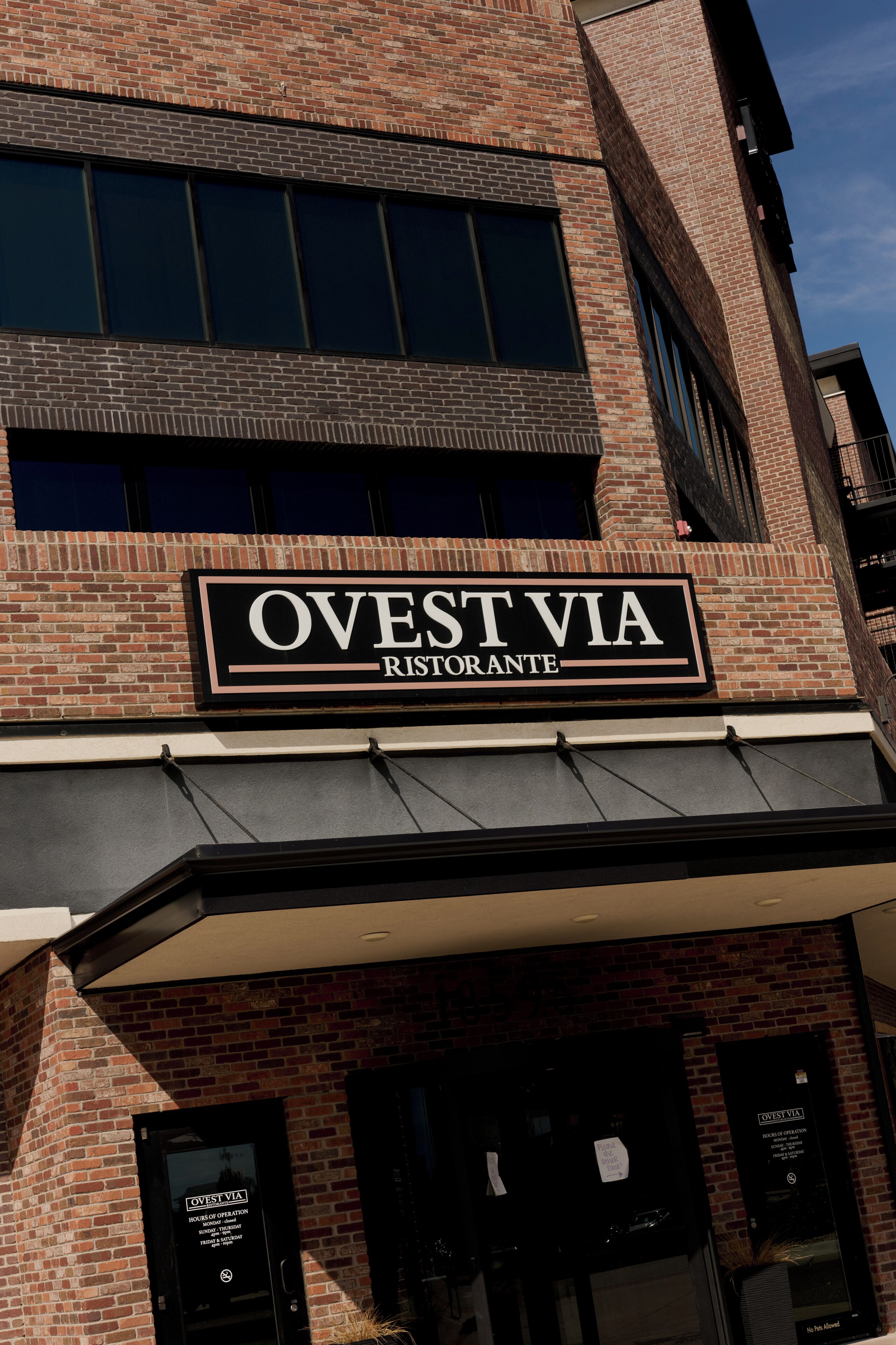 En byggnad av tegel med en skylt som visar texten ”OVEST VIA RISTORANTE”, vilket indikerar att det är en restaurang.