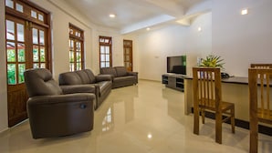 A spacious living room with a sofa set, a TV, and a wooden dining table with chairs. - Niru Residence (Kandy)