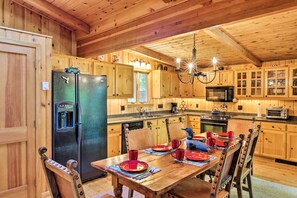 Una cocina de estilo cabaña de madera con una mesa de comedor preparada para cuatro personas, un refrigerador y un microondas.