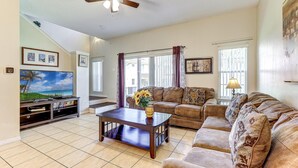 A living room with a television, sofa, coffee table, and ceiling fan. - Unit 15 | 3BR Home | 2 Mi to Disney | Pet Friendly | Heated Pool | Gated (Kissimmee)