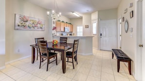 A dining area with a wooden table and chairs, a chandelier, and a painting on the wall. - Unit 15 | 3BR Home | 2 Mi to Disney | Pet Friendly | Heated Pool | Gated (Kissimmee)