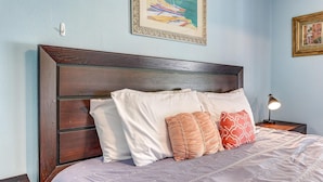 A bedroom with a wooden headboard, a bed with a purple bedspread, and two nightstands with lamps. - Unit 15 | 3BR Home | 2 Mi to Disney | Pet Friendly | Heated Pool | Gated (Kissimmee)